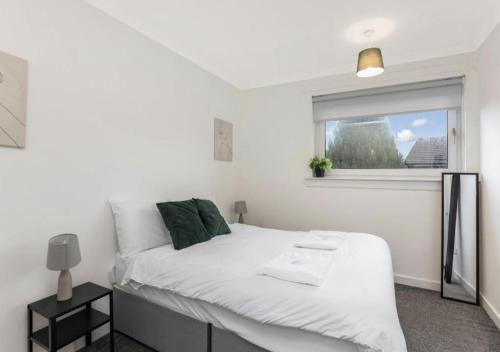 a white bedroom with a bed and a window at Celtic City Stay in Glasgow