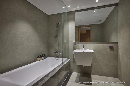 a bathroom with a tub and a sink and a shower at Hotel Interciti in Daejeon