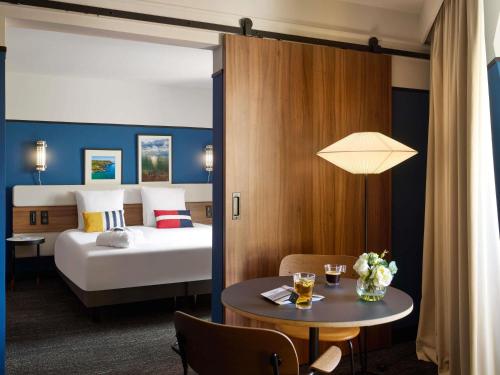 a hotel room with a bed and a table with a table at Mercure Caen Centre Port De Plaisance in Caen