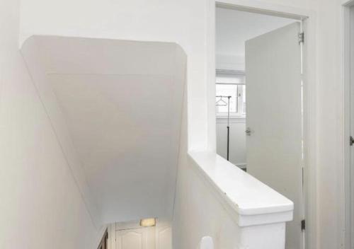 a white bathroom with a staircase and a mirror at Celtic City Stay in Glasgow