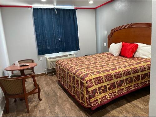 a bedroom with a bed and a table and a chair at Broadway Inn Motel in Los Angeles