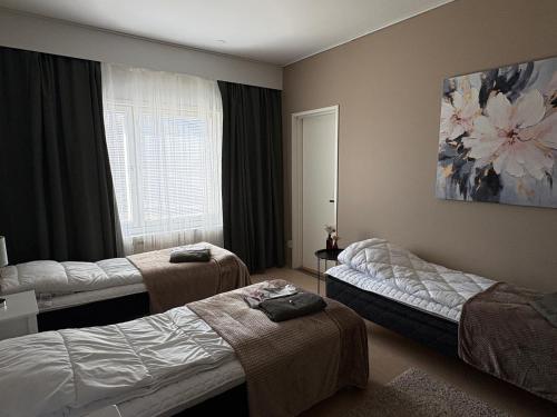 ein Hotelzimmer mit drei Betten und einem Fenster in der Unterkunft Guesthouse Terkkari in Lahti