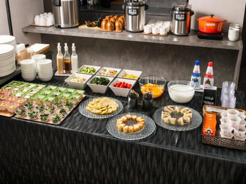 ein Buffet mit vielen verschiedenen Speisen auf einem Tisch in der Unterkunft THE STILL HOTEL - Opening April 3, 2026 in Ozu