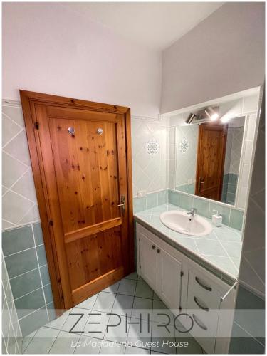 a bathroom with a sink and a wooden door at Zephiro Guest House in La Maddalena