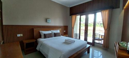 a bedroom with a large bed and a balcony at Umayuri Inn in Ubud