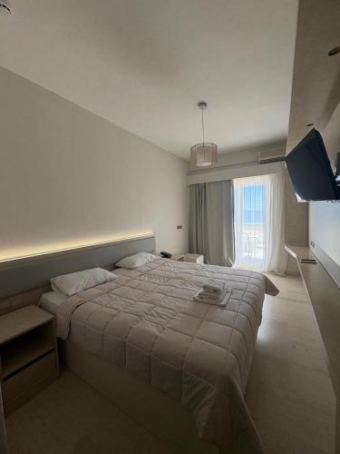 a bedroom with a large bed and a large window at Zakros Beach hotel in Tolo