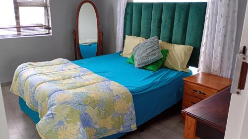 a bedroom with a blue bed with a green headboard at Leisure Seaview House in Port Edward