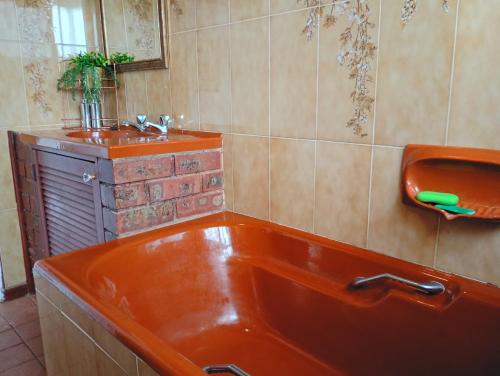 a bathroom with an orange tub and a sink at Leisure Seaview House in Port Edward