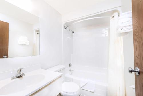 a white bathroom with a sink and a toilet at Super 8 by Wyndham Belle Fourche SD in Belle Fourche