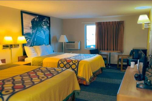 a hotel room with two beds with yellow sheets at Super 8 by Wyndham Belle Fourche SD in Belle Fourche