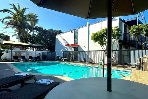 a swimming pool with a table and an umbrella at Days Inn by Wyndham Los Angeles LAX Airport Stadium Area in Los Angeles