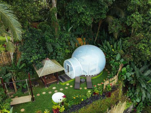 a small garden with a blue object in the grass at Bubble 6 - Romantic Bath Bubble Stay Ubud in Tampaksiring