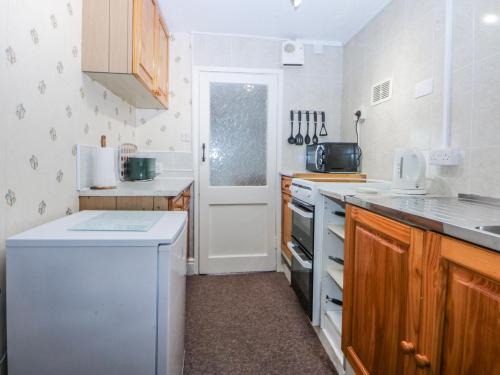 a kitchen with a white refrigerator and a dishwasher at Ground Floor Apartment in Porthmadog