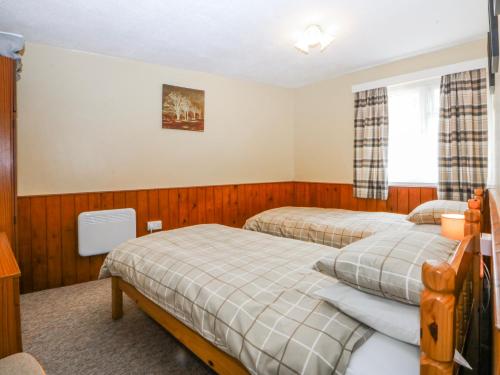 a bedroom with two beds and a window at Ground Floor Apartment in Porthmadog