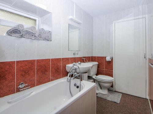 a bathroom with a tub and a toilet and a sink at Ground Floor Apartment in Porthmadog