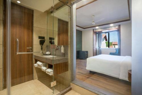 a bedroom with a bed and a glass shower at Radisson Resort & Spa Sasan Gir in Junagadh