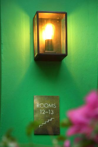 a light on a green wall with a clock on it at The Grey Hotel in Cape Town
