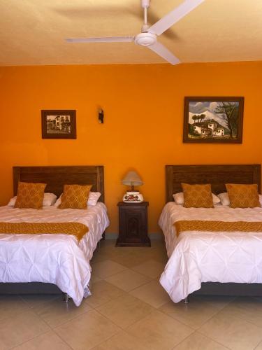 two beds in a room with orange walls at CASONA DOS VIDAS in El Sauz Tequisquiapan