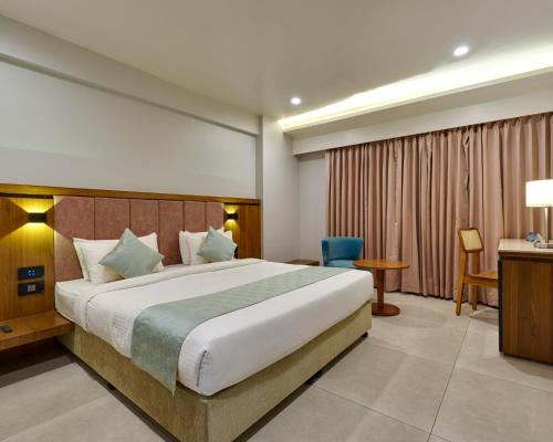 a hotel room with a large bed and a desk at The Qubice Hotel, Kolhapur in Kolhapur