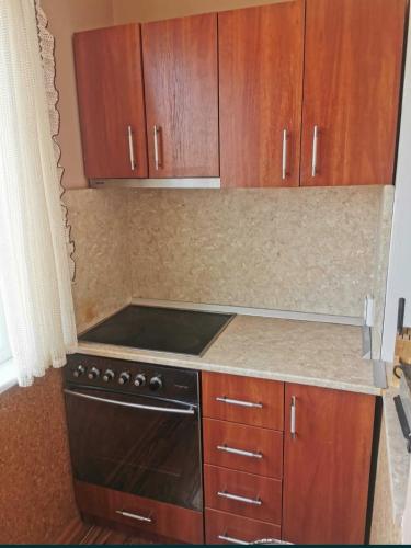 a kitchen with a black stove and wooden cabinets at Mountain view apartment in Vratsa