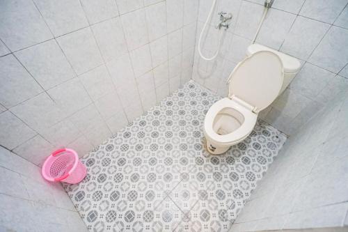 a bathroom with a toilet and a pink bucket at Homestay Putri Kencono in Yogyakarta