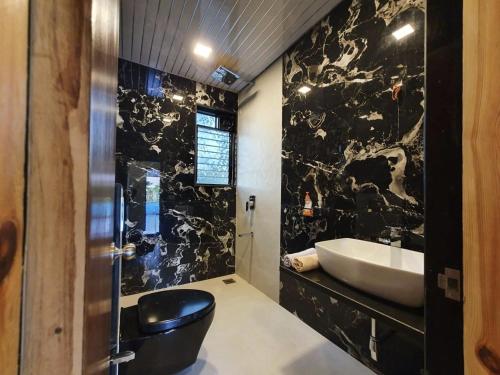 a bathroom with a sink and a black wall at Lake Side Mantra in Khamshet