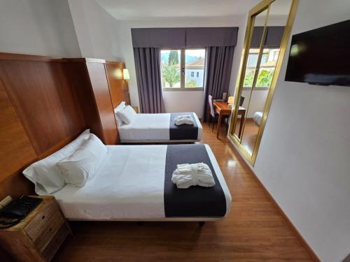 a hotel room with two beds and a mirror at Hotel Saylu in Granada