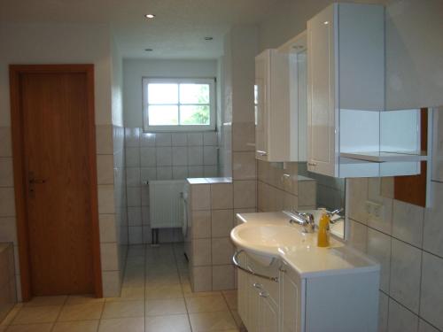 a white bathroom with a sink and a window at Zollhaus in Bad Elster