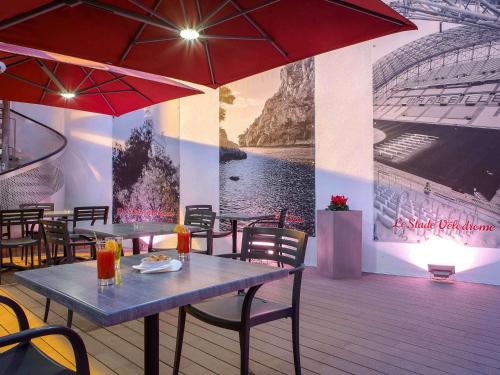 a restaurant with tables and umbrellas and a mural at ibis Marseille Timone in Marseille