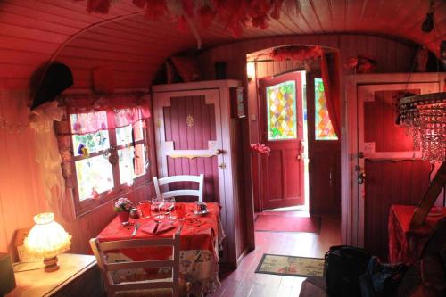 a red dining room with a table and a red door at La Roulotte De Lola - Chambre d'hôtes in La Celle