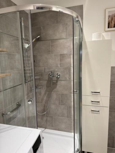a shower with a glass door in a bathroom at Apartament Aria in Ełk