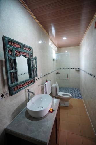 a bathroom with a sink and a toilet and a mirror at The Galuh Pekutatan in Pulukan