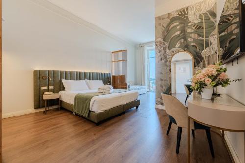 a bedroom with a bed and a table and a desk at Lolli Palace Hotel in Sanremo