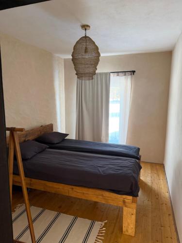 a bedroom with a bed with blue sheets and a window at Clay House in Pāvilosta