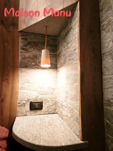 Eine Steinmauer mit einer Lampe und einem Schild mit der Aufschrift „Mason Mannum“ in der Unterkunft Maison Manu in Perosa Argentina