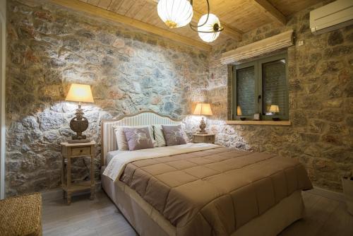 a bedroom with a bed in a room with stone walls at Villa with private pool and stunning sea view in Galaxidi
