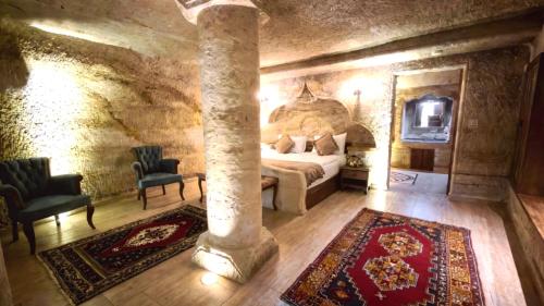 a bedroom with a bed and two chairs in a room at Göreme Rock Cave in Göreme
