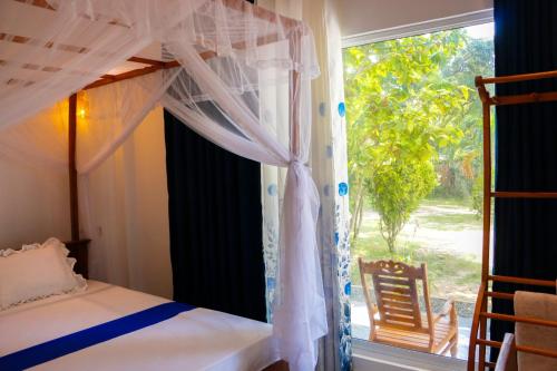a bedroom with a canopy bed and a window at Malika homestay in Midigama East