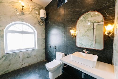 a bathroom with a sink and a toilet and a window at Soma Jawai in Bijāpur