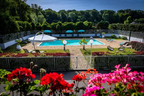 a swimming pool in a garden with pink flowers at Hotel La Chaumiere in Dole