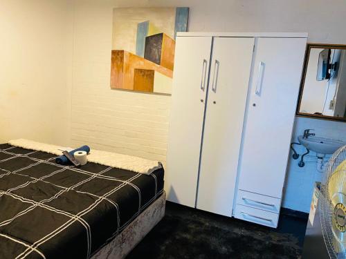 a bedroom with a bed and a white cabinet at GLOBALNEST guest house in Cape Town