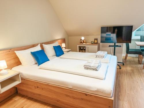 a bedroom with a large white bed with blue pillows at Apartmenthaus Leuchtfeuer in Norderney