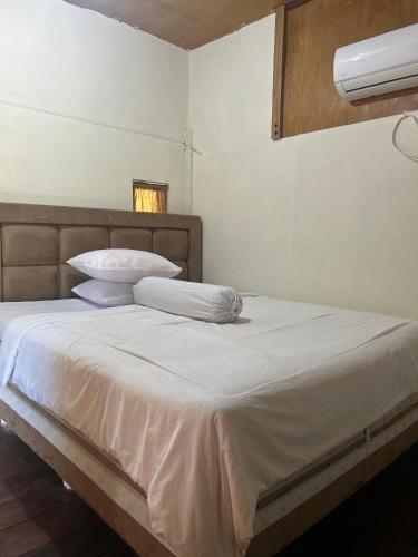 a bedroom with a bed with white sheets and pillows at Tiu Batu Homestay in Bangsal