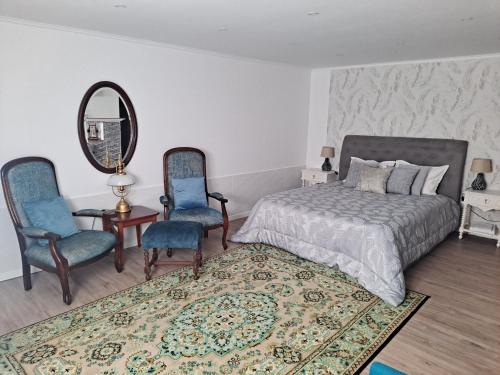 a bedroom with a bed and two chairs and a mirror at Casa Do Cais in Setúbal