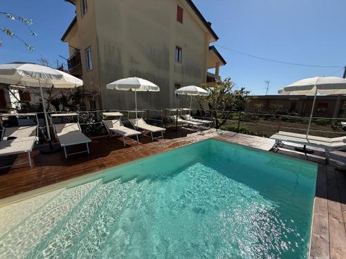 a swimming pool with chairs and umbrellas next to a building at Home & Garden in Vico Equense