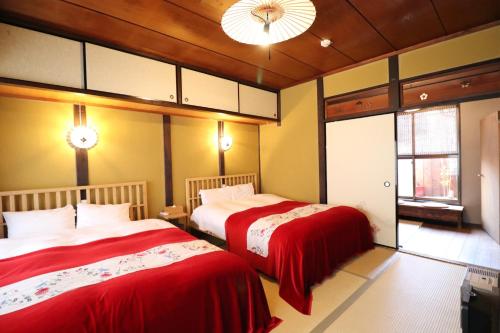 a bedroom with two beds with red covers in it at TSUDOYA Tennoji 集家天王寺 in Osaka