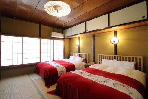two beds in a room with two windows at TSUDOYA Tennoji 集家天王寺 in Osaka