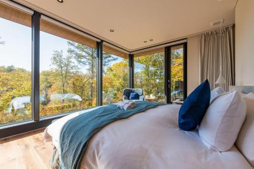 a bedroom with a large bed and large windows at Sena 惺絆 in Niseko