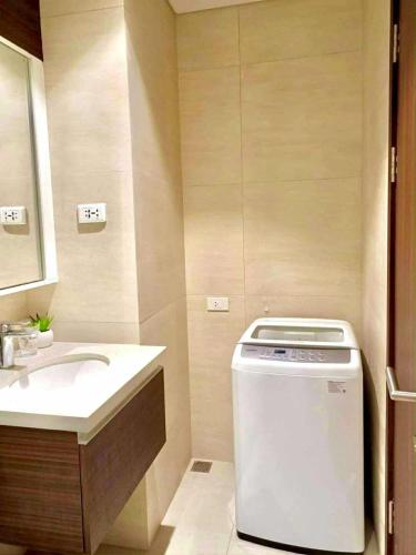a bathroom with a sink and a washing machine at Seaside Living Studio Unit in Maribago