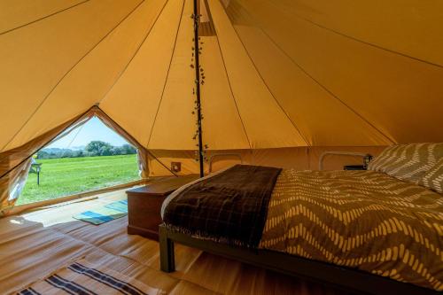 a bed in a tent with a large window at Furnished Bell Tent 1 in St Austell